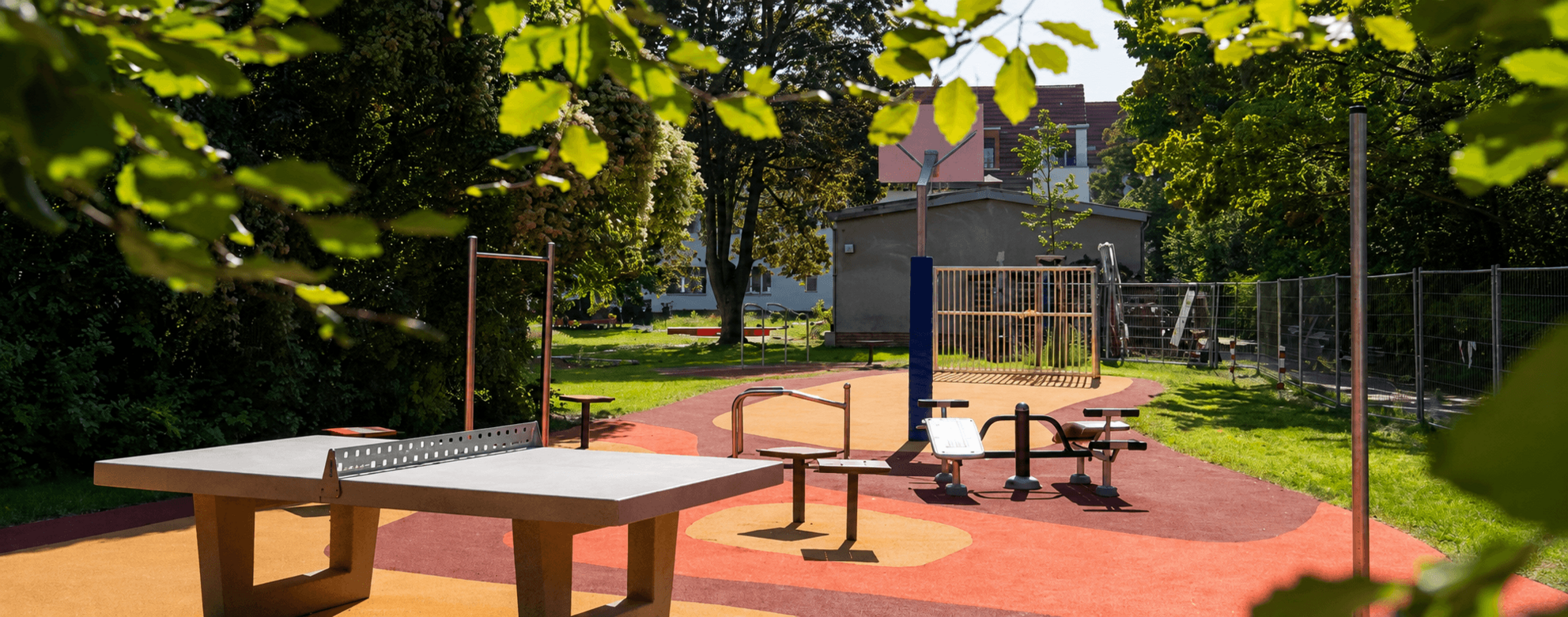 Accessible playground in Berlin-Steglitz-Zehlendorf with REGUPOL impact-absorbing safety surfacing, fitness equipment, table tennis facilities, and an inclusive play and recreation area for children, families, and adults.